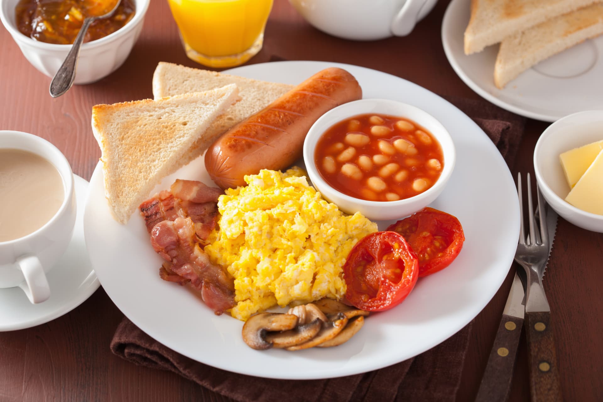Plato de desayuno con huevos revueltos, salchicha, tocino, frijoles y pan tostado