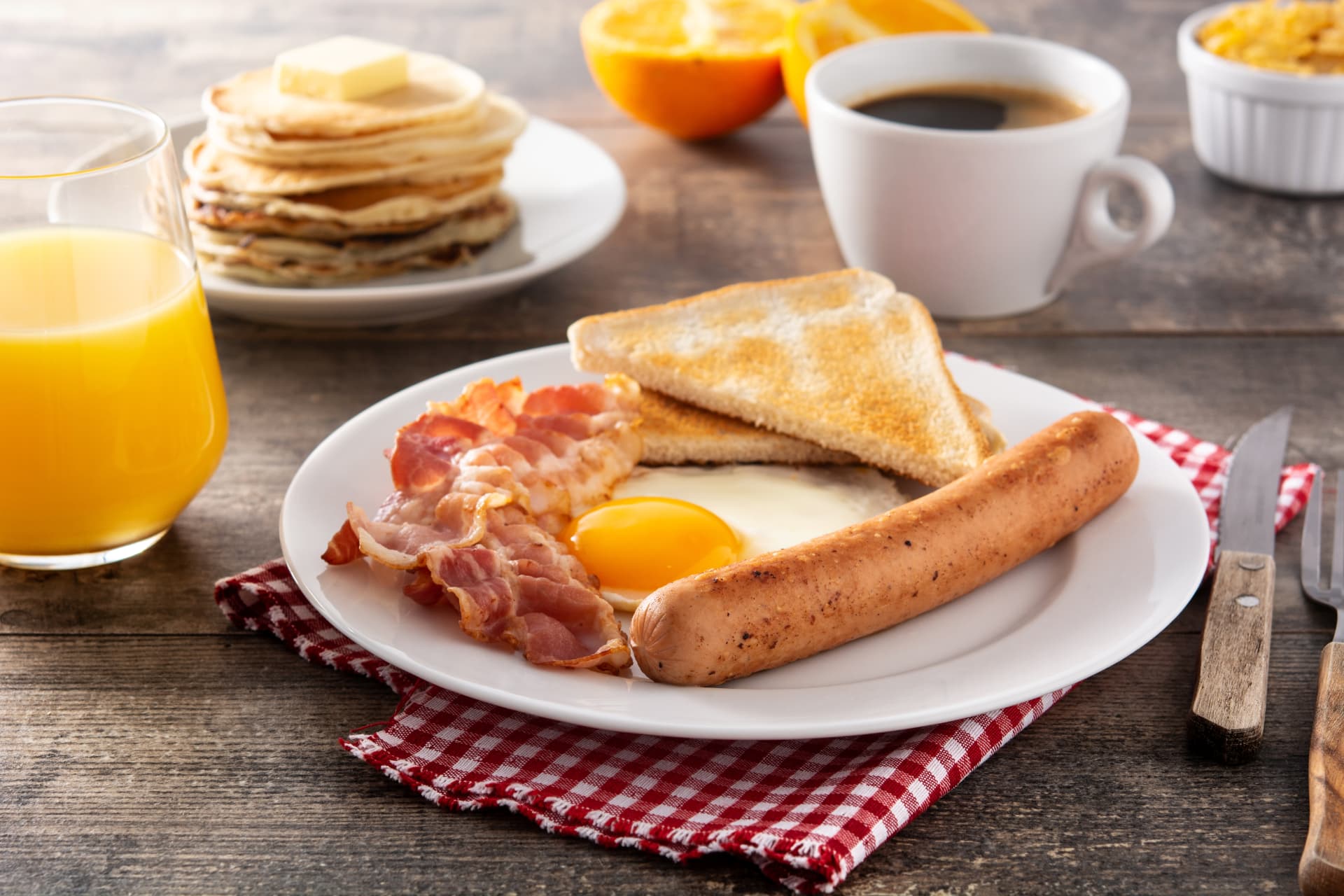 Desayuno americano con huevo frito, tocino, salchicha, pancakes y café