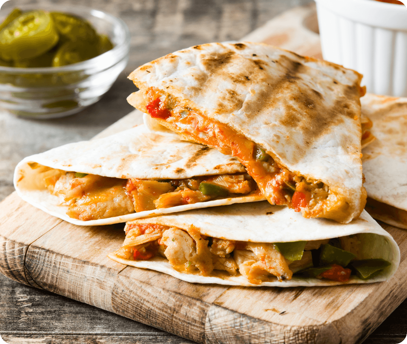 Quesadillas de pollo a la parrilla con pimientos y queso derretido sobre tabla de madera