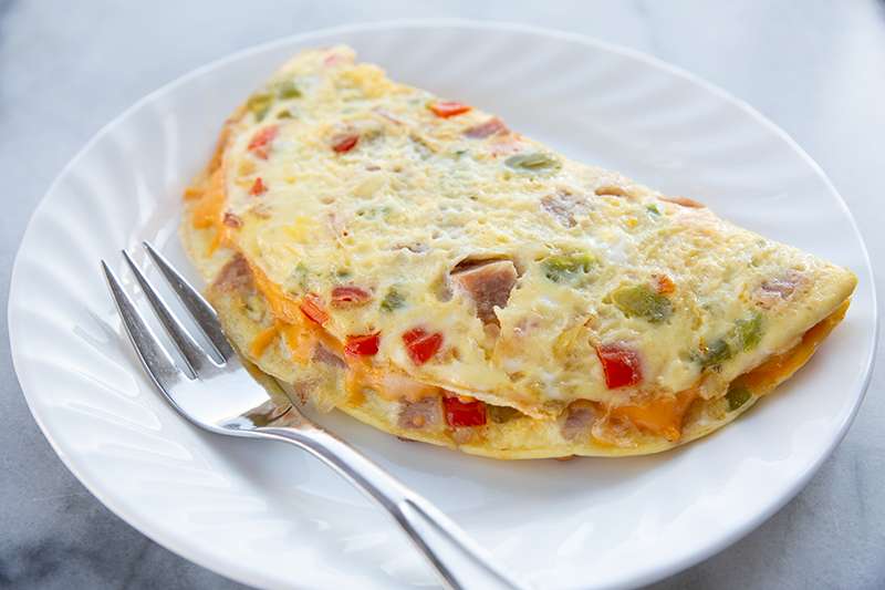 Western omelet con jamón, pimientos y queso cheddar en un plato blanco